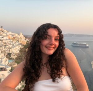 Charlotte Carter is standing outside with the ocean in the background. 