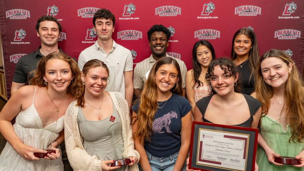 A large group of kids stand and smile in front of a maroon Lafayette backdrop